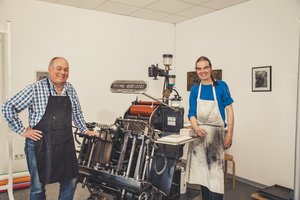 Manfred Becker (links) und Christoph Hoppe von der Druckwerkstatt vor dem Original Heidelberger Tiegel.